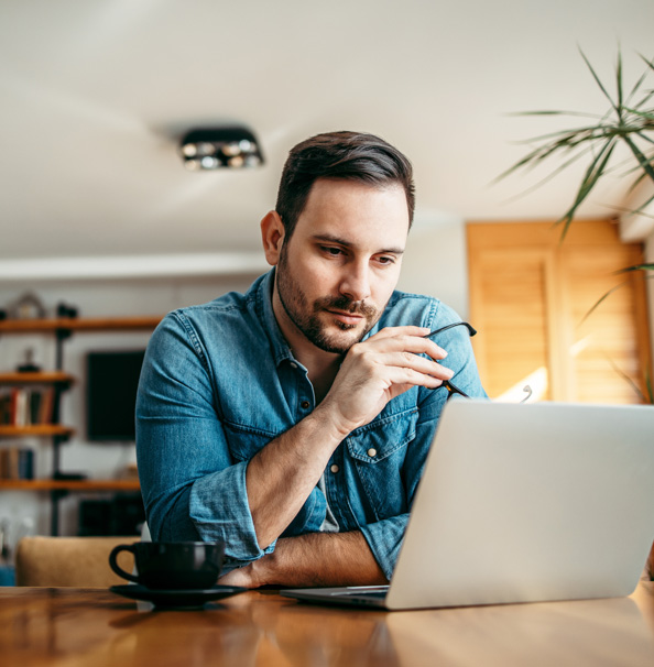 Man focused on laptop, coffee nearby.