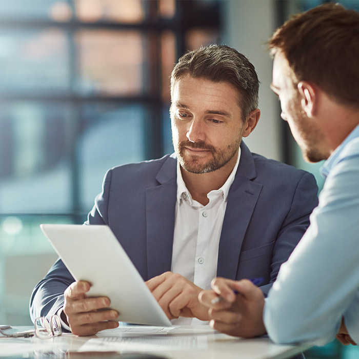 Two men discussing over a tablet.