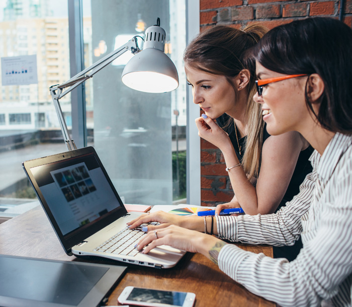 Two women collaborating over a laptop.