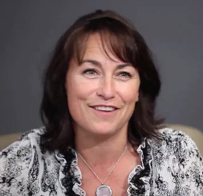 Smiling woman in patterned blouse.