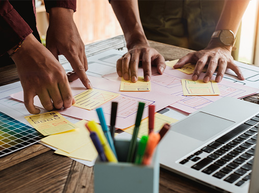 Hands over design mockups and notes.