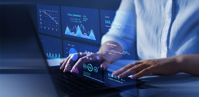 Hands typing on a laptop displaying graphs and data.