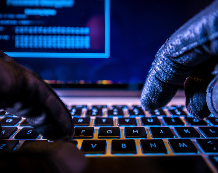 Hands in gloves typing on laptop.