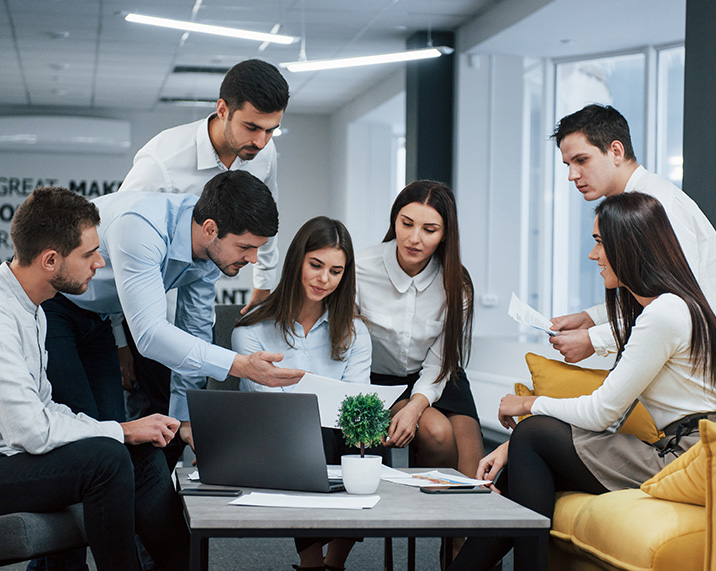 Group of people collaborating around a laptop.