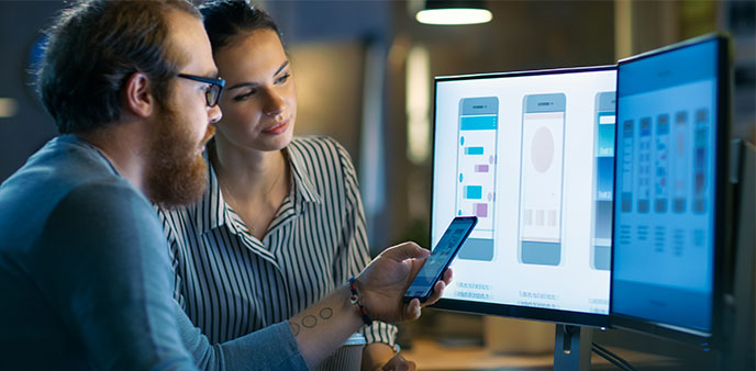 Man and woman reviewing mobile app designs.