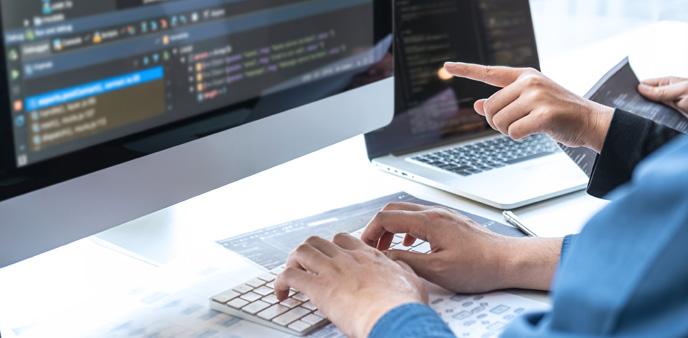 Hands typing on keyboard, screen displaying code.