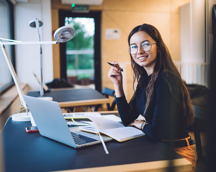Smiling woman with glasses at a desk.