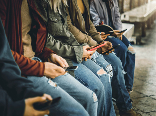 Group of people sitting, using smartphones.